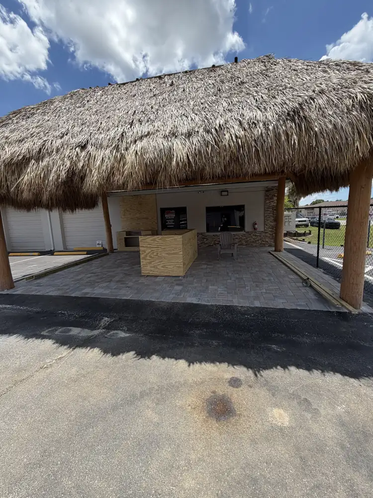 Paver patio beneath a tiki-roof storefront in Port Charlotte, Florida
