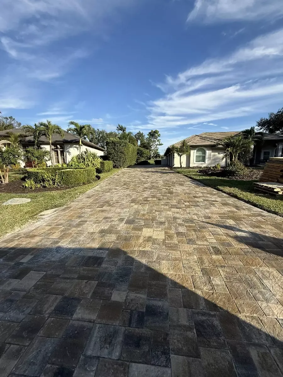Long gray concrete paver driveway running toward the street at a Sarasota, Florida home