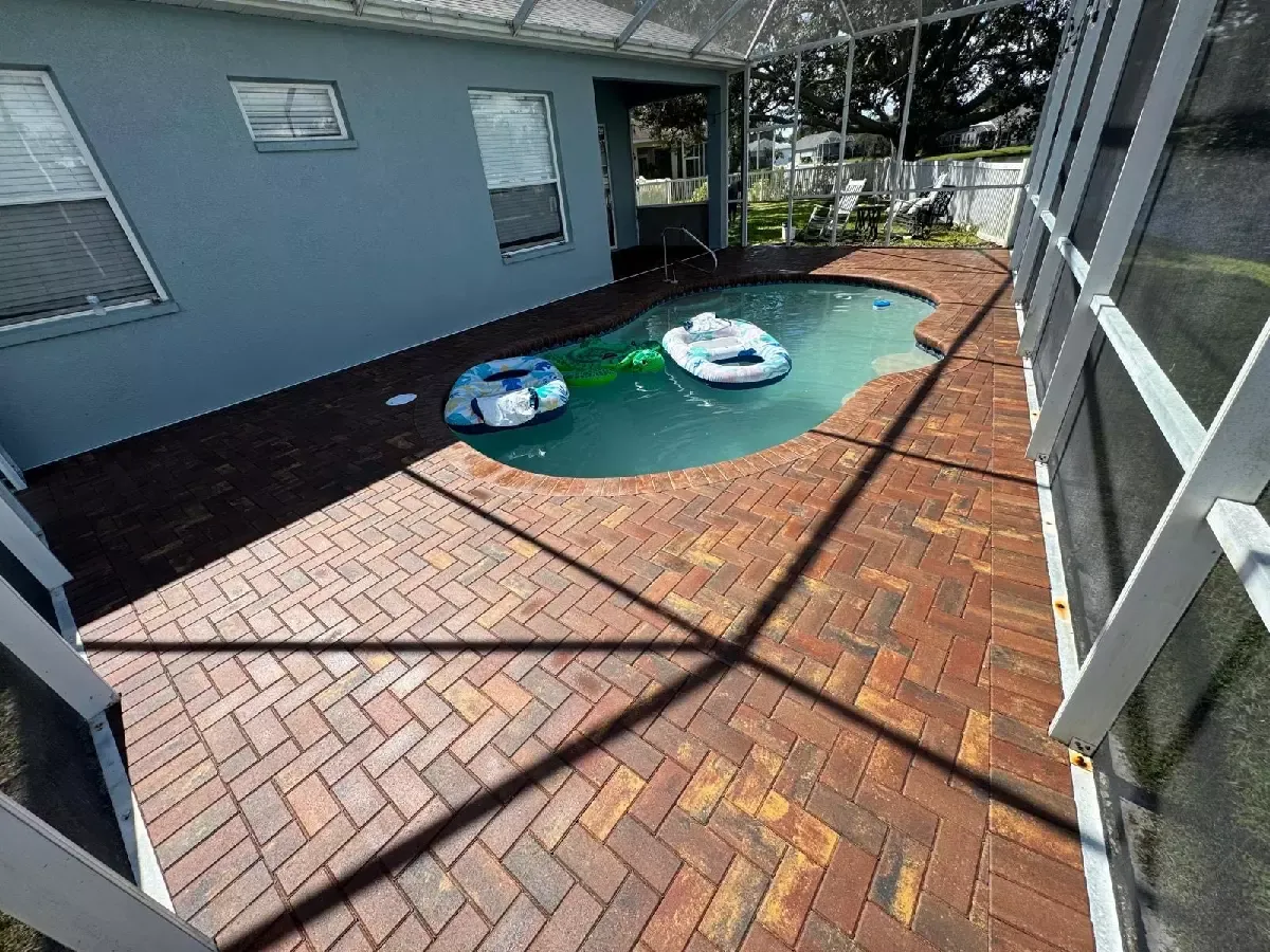 Brick paver pool deck surrounding a screened in-ground pool in Sarasota, Florida