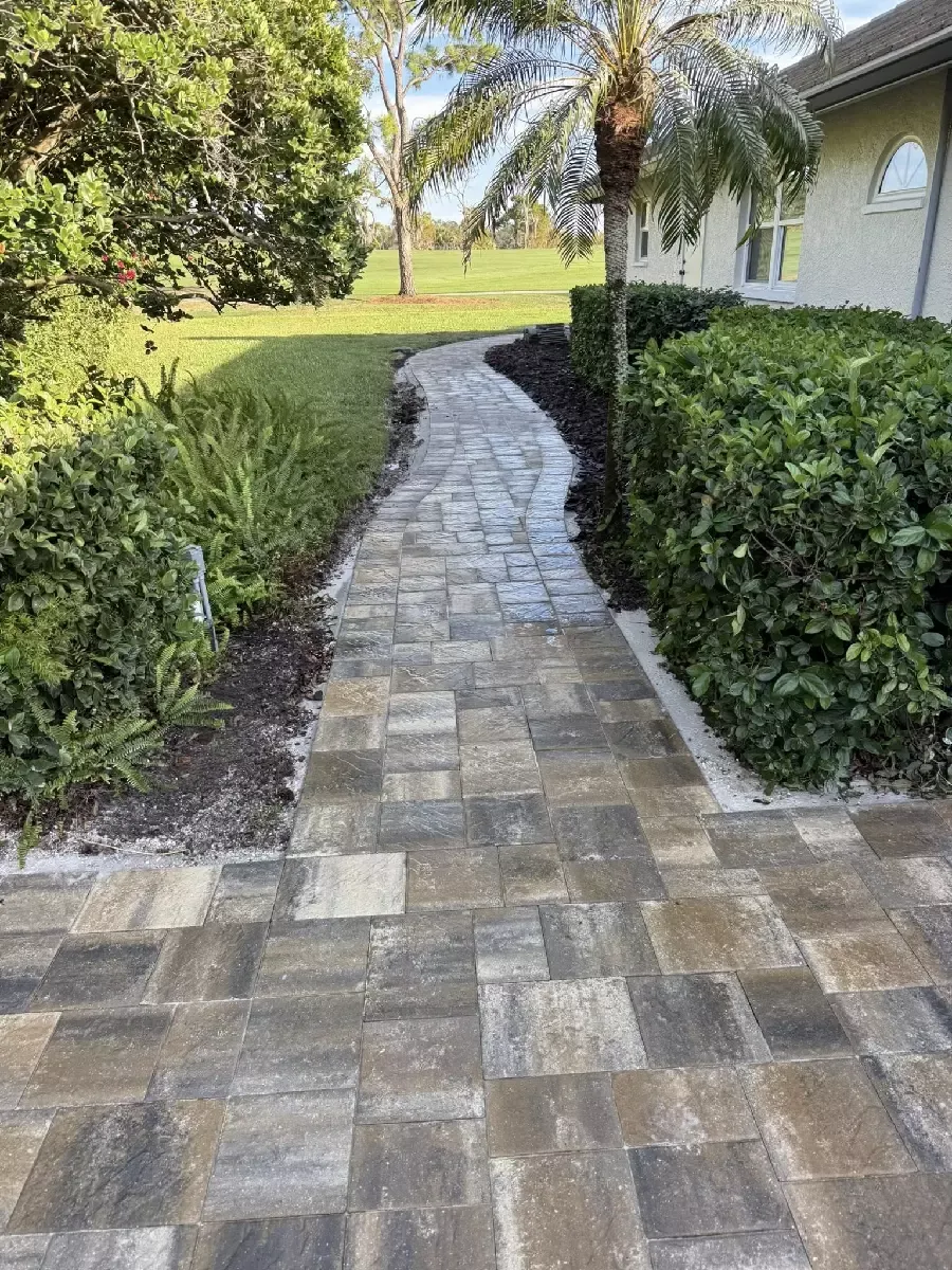 Curved concrete paver walkway beside a residential home and landscaping in Sarasota, Florida