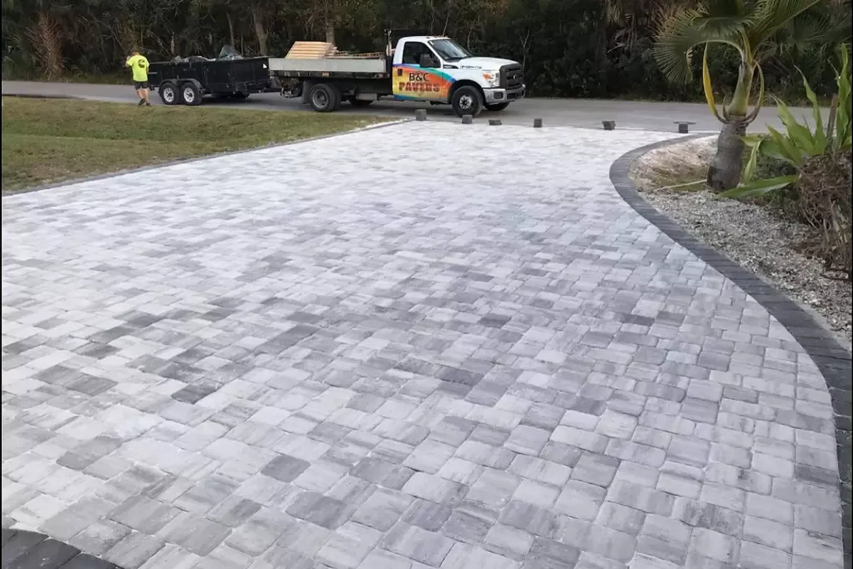 Curved gray concrete paver driveway with a dark border and a B&C Pavers truck in Venice, Florida