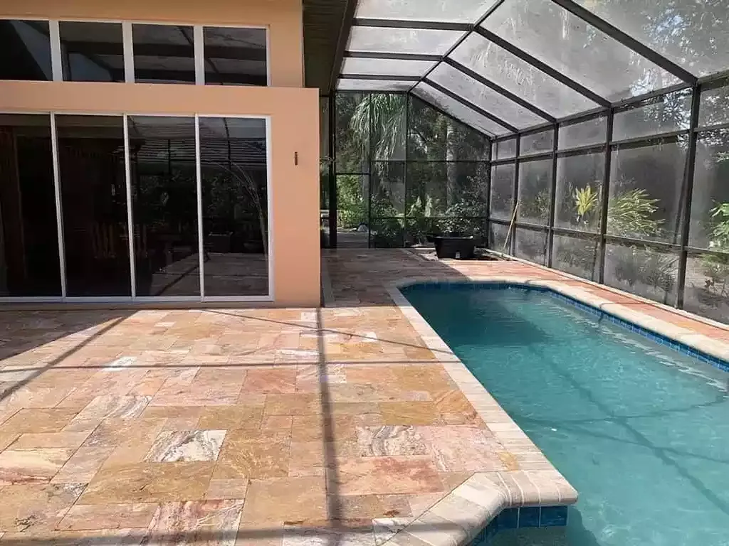 Paver pool deck inside a screened lanai enclosure at a Venice, Florida home
