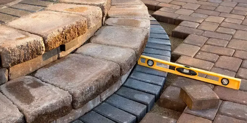 Contractor leveling a curved paver ledge during a paver repair in Venice, Florida
