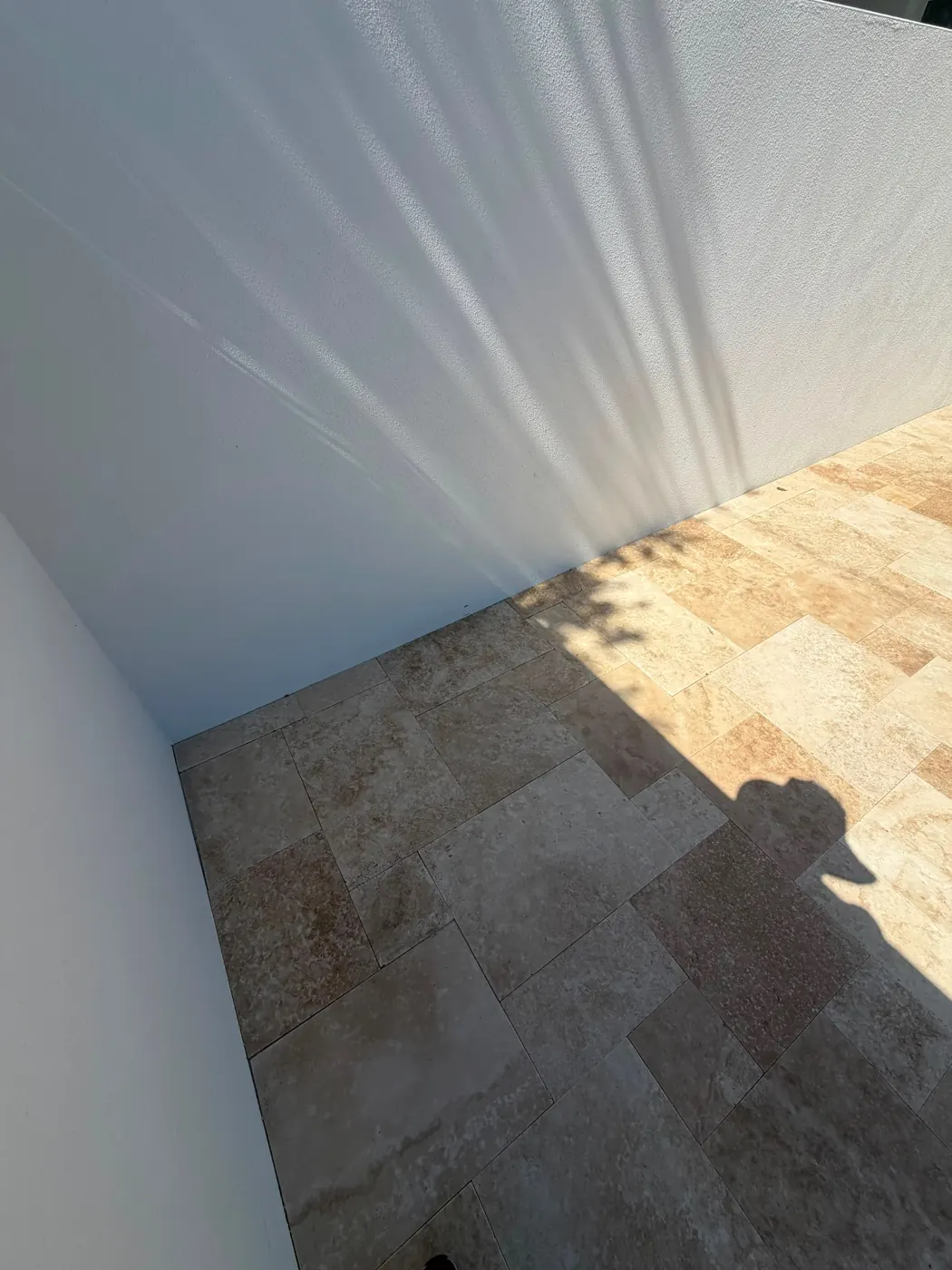 Close-up of ivory French-pattern travertine pool decking in Venice, Florida